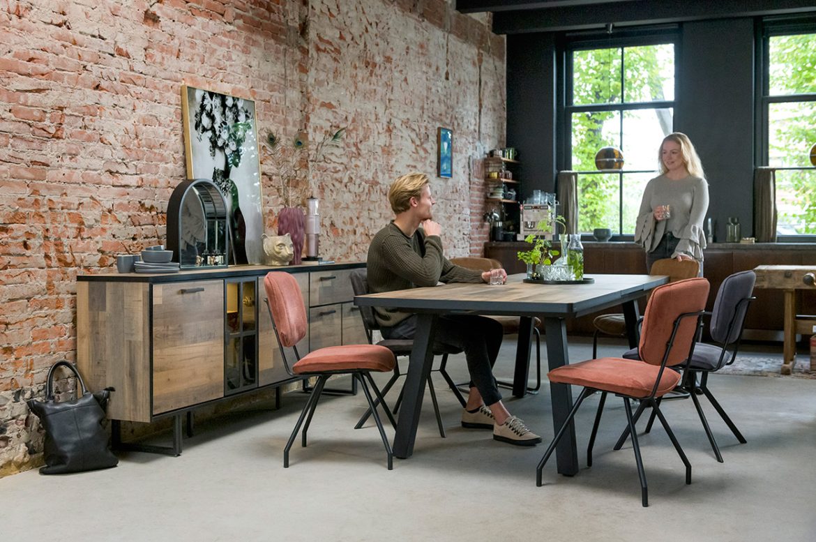 Un intérieur moderne avec un élégant buffet industriel en bois et métal, complété par une table à manger et des chaises colorées.