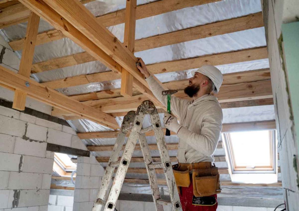 Artisan travaillant sur la charpente d'un toit, étape clé de toute rénovation maison.