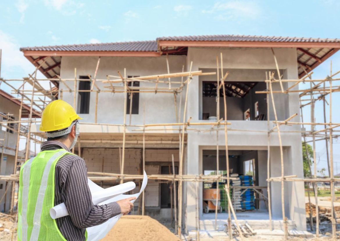 Ingénieur avec casque de sécurité examinant les plans d'une construction maison en cours.