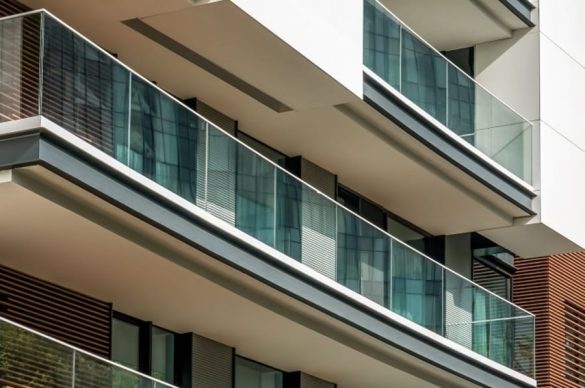 Façade moderne d'un immeuble résidentiel équipée d'un garde-corps en verre extérieur sans cadre offrant une vue dégagée
