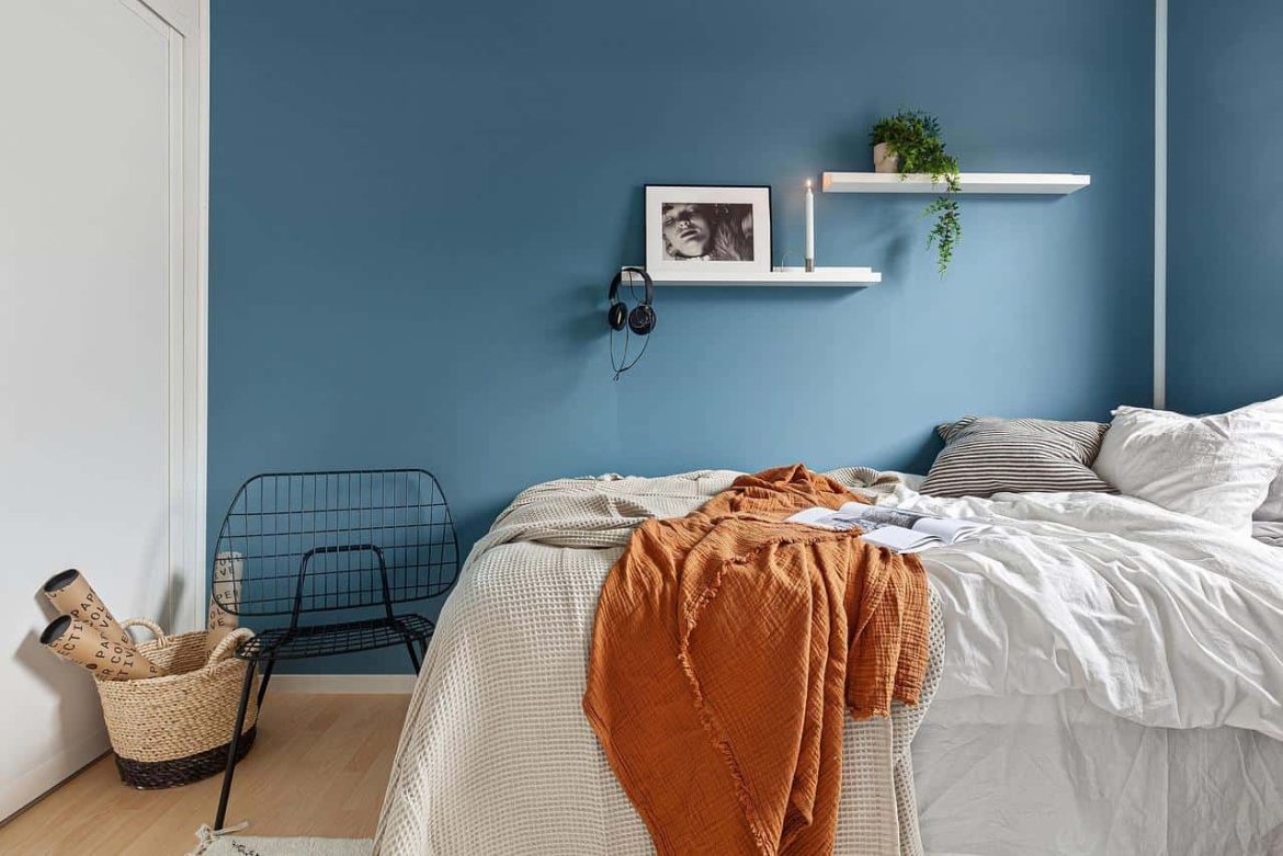 Une moustiquaire de lit 2 places installée au-dessus d'un lit double dans une chambre au mur bleu scandinave