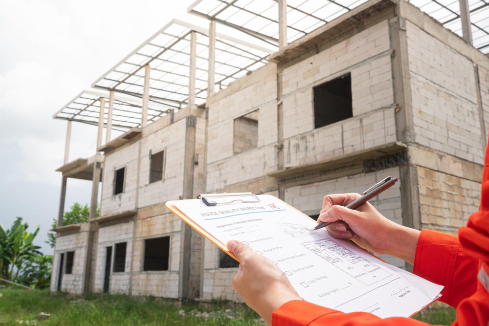 Inspecteur de travaux vérifiant la conformité sur le chantier d'un projet de terrain et maison en bretagne