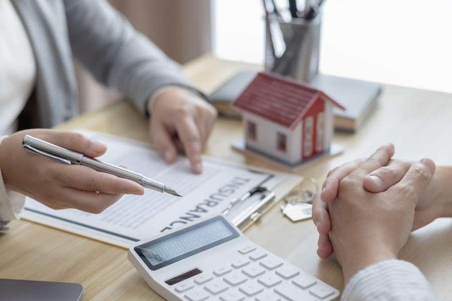 Une personne en consultation avec un conseiller, avec une calculatrice et une maison miniature, pour aborder la fiscalité de vos revenus locatifs.