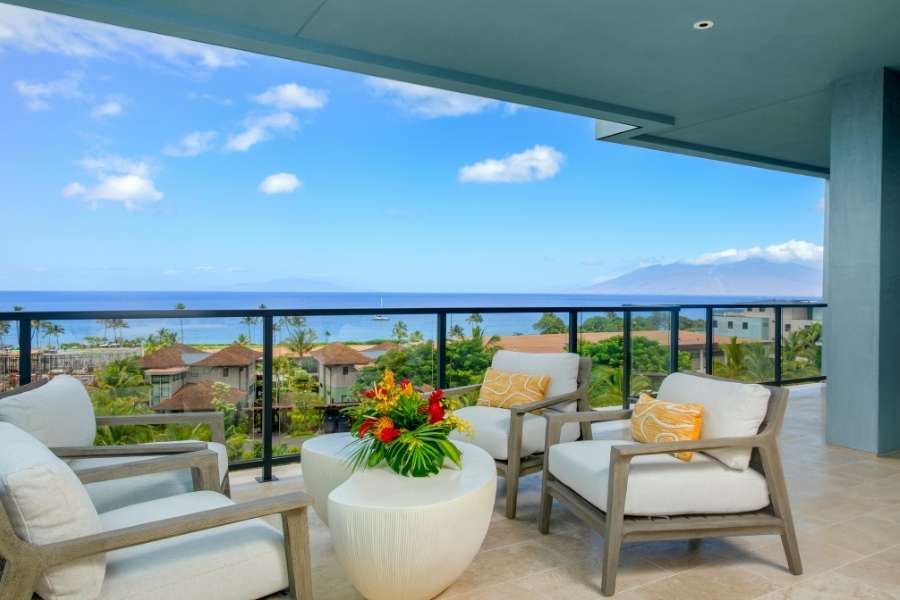 Un balcon luxueux avec vue sur la mer, décoré de fauteuils confortables et d'une table basse.