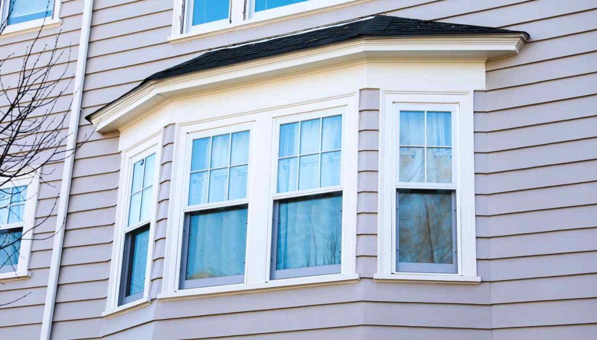 Gros plan sur une nouvelle fenêtre de baie en PVC blanc installée sur un revêtement de maison gris dans le cadre d'une renovation fenetre menuiserie pvc prime energie.